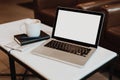 Front view. Empty workplace. On white coffee table is laptop with blank screen, cup of coffee, notebook, pen, newspaper. Royalty Free Stock Photo