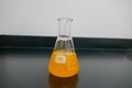 Front view of erlenmeyer with orange chemical solution and white background