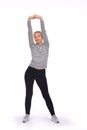 The young girl exercises by stretching and raising both her arms up. Front view