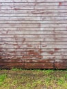 Front view of exterior wooden wall with wild green weeds. Wall of horizontal wooden slats on a grass floor. Close up of old fence Royalty Free Stock Photo