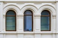 A facade of ancient stone building with three arched windows with carved platbands Royalty Free Stock Photo