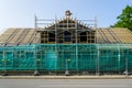 Front view of the facade of a wooden house under restoration with scaffolding and safety net Royalty Free Stock Photo