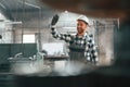 Front view. Factory male worker in uniform is indoors