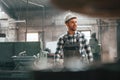 Front view. Factory male worker in uniform is indoors