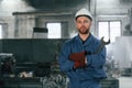 Front view. Factory worker in blue uniform is indoors