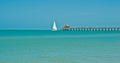 sailboat, sailing past a wood pier , in the tropical waters