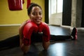 Front view of African athlete, female boxer in boxing red gloves performing a twine on the floor of a sport gym with a boxing Royalty Free Stock Photo