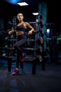 Woman leaning on stand with barbells.