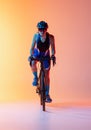 Front view. Female cyclist riding a bicycle isolated against neon background Royalty Free Stock Photo