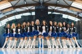 Front view of female group of cheerleaders standing in v formation in sports hall.