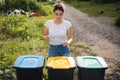 Front view of female throwing out in recycling bin clean empty plastic container. Different colour of recycling bins