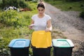 Front view of female throwing out in recycling bin clean empty plastic container. Different colour of recycling bins