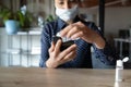 Cautious young woman wearing medical facemask, killing bacteria on smartphone.