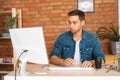 Front view of focused handsome young freelance programmer male working on desktop computer sitting at desk at home Royalty Free Stock Photo