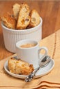 Front view of freshly baked, homemade, apricot ginger walnut biscotti on a small, white, round plate and a cup of espresso Royalty Free Stock Photo