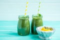 Front view of freshly blended green smoothie with mango in glass jars. Turquoise blue background Royalty Free Stock Photo