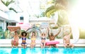 Front view of friends sitting at pool party with lilo airbed and swim wear - Summer lifestyle concept with happy guys and girls