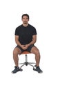 Front view of a full portrait of a man sitting on a chair, looking at camera wearing sportswear on white background Royalty Free Stock Photo