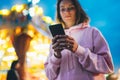 Front view girl pointing finger on screen smartphone on defocus background bokeh light in evening street attraction, woman using Royalty Free Stock Photo