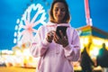 Front view girl pointing finger on screen smartphone on defocus background bokeh light in evening street attraction, woman using Royalty Free Stock Photo