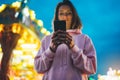 Front view girl pointing finger on screen smartphone on defocus background bokeh light in evening street attraction, woman using Royalty Free Stock Photo