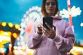 Front view girl pointing finger on screen smartphone on defocus background bokeh light in evening street attraction, woman using Royalty Free Stock Photo