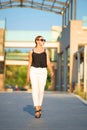 Front view of going woman on blur background of summer street. Female tourist walking along tropical resort hotel building Royalty Free Stock Photo