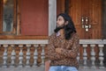 Front view a good looking long haired young guy looking sideways while sitting in old temple posing with crossed arms