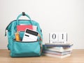 Front view of green backpack with school supplies, stack of books and wooden calendar September 01 on wooden table and white Royalty Free Stock Photo