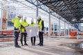 Group of engineers with blueprints standing on construction site. Royalty Free Stock Photo