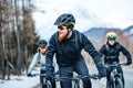 Front view of group of mountain bikers riding on road outdoors in winter. Royalty Free Stock Photo