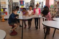 Group of schoolkids studying together at table in school library