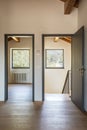 Front view hallway with open doors, one to an empty room and the other to the stairs. Paquet floor and white walls. Nobody inside Royalty Free Stock Photo