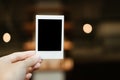 front view. hand of young woman holding blank Polaroid film. have blur interior cafe are background. image for abstract,body part Royalty Free Stock Photo