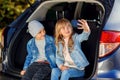 Front view of handsome 10-aged boy in hat and pretty 12-aged girl with blond long hair which taking photos on her phone Royalty Free Stock Photo