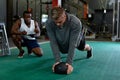 Male trainer writing on clipboard while male athletic exercising with exercise ball