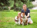 Joyful man sitting on grass with dogs.