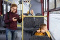 Cheery man in glasses with backpack checking phone inside public bus in winter. Royalty Free Stock Photo