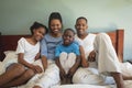 Happy African American family looking at camera while relaxing on bed in bedroom Royalty Free Stock Photo