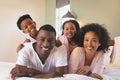 Happy African American family lying on bed and looking at camera Royalty Free Stock Photo