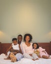 Happy African American family relaxing on bed and looking at camera Royalty Free Stock Photo
