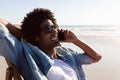 Man talking on mobile phone while relaxing in a beach chair on the beach Royalty Free Stock Photo