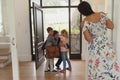 Father embracing his children as he enters the house while mother looking them Royalty Free Stock Photo