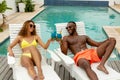 Couple toasting glasses of cocktail while relaxing on a sun lounger near swimming pool Royalty Free Stock Photo