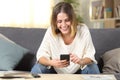 Front view of a happy girl using mobile phone on a sofa Royalty Free Stock Photo