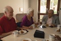 Front view of happy group of senior friends having breakfast on dining table Royalty Free Stock Photo