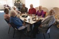 Front view of happy group of senior friends sitting on dining table and looking at camera Royalty Free Stock Photo