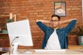 Front view of happy handsome young freelance programmer male in stylish glasses holding hands behind head sitting at Royalty Free Stock Photo