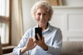 Happy 70s grandmother taking selfie on smartphone.