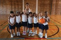 Happy schoolkids and female coach looking at camera at basketball court